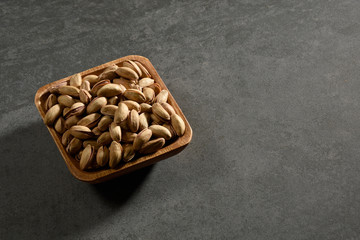Pistachio nuts in a wooden bowl with copy space, still life