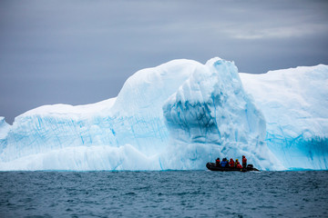  Zodiac cruise ship in Antarctica in front of a large iceberg in the ocean  © Gabi