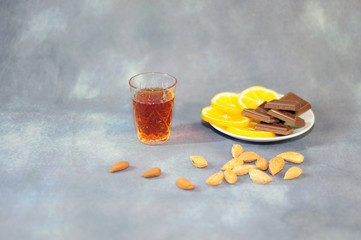 Crystal glass with cognac plate with lemon slices chocolate slices and a scattering of nuts on a...