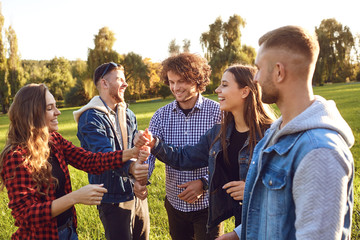 Group of friends connected thumb up in the park.