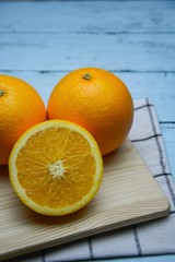 Fresh and juicy half and slice of orange fruit on a chopping block on weathered wooden table background,Orange on the cutting board in the face,