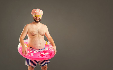 Thick funny man with a beard with a circle for swimming on a background.