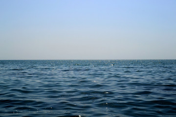 Nature background. Drops of water on the surface of the blue sea glow under the sun