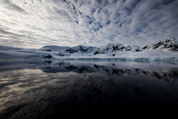 Fototapeta na wymiar Snow and ice of the mountains reflected in the water in Antarctica, a pristine remote landscape