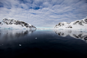 Fototapeta na wymiar Snow and ice of the mountains reflected in the water in Antarctica, a pristine remote landscape