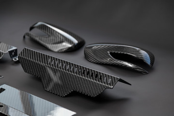 A close-up on a car exterior elements made from carbon fiber of interwoven black and gray color...