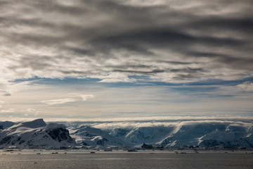Snow and ice on the mountains near the water in Antarctica, a pristine remote landscape