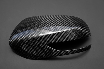 A close-up on a car exterior mirror made from carbon fiber of interwoven black and gray color from...