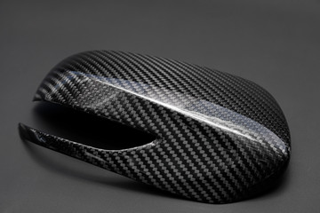 A close-up on a car exterior mirror made from carbon fiber of interwoven black and gray color from...
