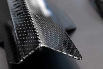 A close-up on a car exterior elements made from carbon fiber of interwoven black and gray color...