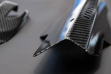 A close-up on a car exterior elements made from carbon fiber of interwoven black and gray color from heavy-duty yarns for the production of light and durable elements in industry. Tuning body parts.