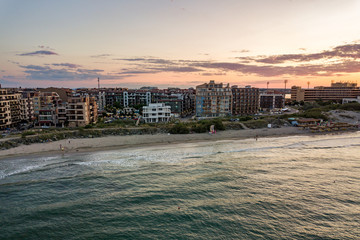 Obraz premium Aerial view of Pomorie city that is located on Black Sea shore. Top view of sand beaches with many hotel buildings and tourist infrastructure.