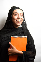 Muslim girl wearing Hijab, hugs orange book and smiling on a white background.