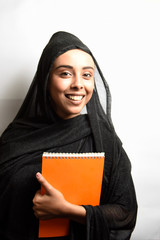 Muslim girl wearing Hijab, hugs orange book and smiling on a white background.