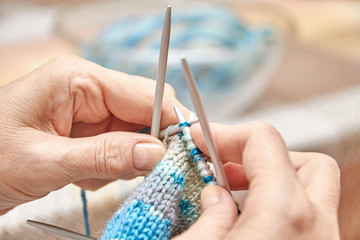 Woman knits socks. A hobby of elderly woman is knitting. Closeup view of knitting loop. Selective focus