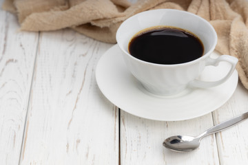 white cup of black coffee with smoke on white table with copy space.