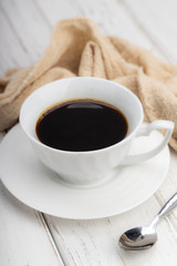 white cup of black coffee with smoke on white table with copy space.