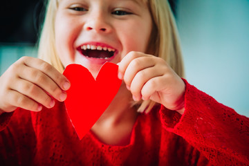 happy little girl holding paper heart in hands