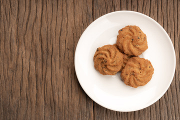 Delicious cookies on a white plate on an old wooden table with copy space.