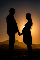silhouette photo of a pregnant women with her husband.