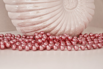 Decor element, pink beads on a white vase in the shape of a shell. Toned high key. Gift for March...