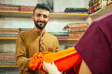 small shop owner indian man selling shawls at his store in arambol goa