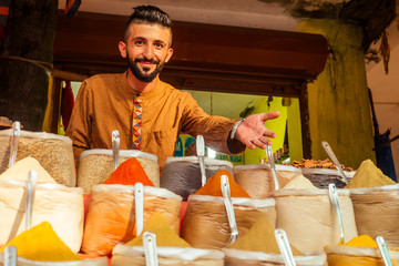 indian sallerman showing his small shop on arambol goa market