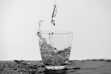 Motion blur of pouring pure drinking water flow into the glass making splash of clearly bubble