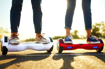 Legs of man and woman riding on the Hoverboard for relaxing time together outdoor at the city. A young couple riding a hoverboard in a park, self-balancing scooter. Active lifestyle technology future.