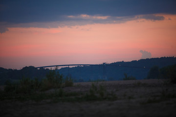 Overpass across the river against a pink sky. Bridge at sunset
