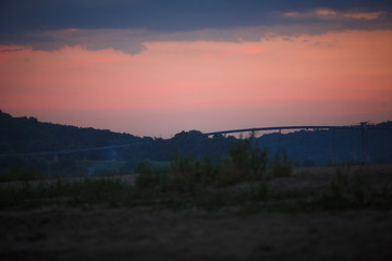Overpass across the river against a pink sky. Bridge at sunset