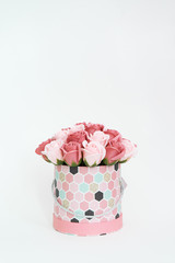 Flowers in bloom: A bouquet of pink and white roses in a round box on a white background.