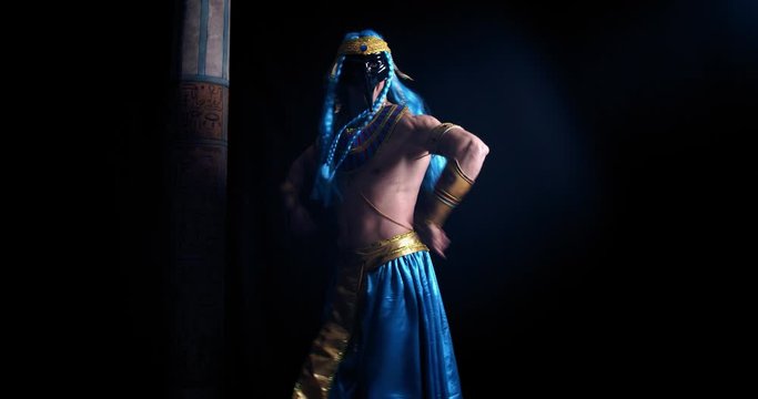 Muscular man in ancient egyptian clothes is dancing on black background, 4k