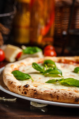talian Cuisine. Classic Italian pizza Margherita with basil, cheese and tomatoes. Serving dishes in a restaurant on a white plate. background image, copy space text