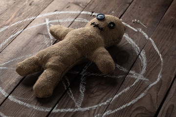 Voodoo doll on a wooden background with dramatic lighting. The concept of witchcraft and black art...