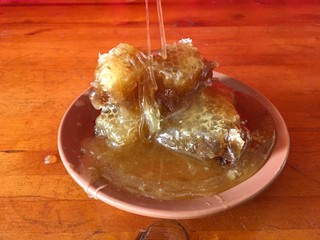 pouring orange honey honeycombs in a clay brown plate on a wooden background