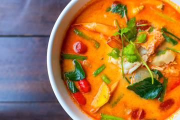 Top view Tom Yam kung Spicy Thai soup with shrimp in white bowl on wood table. With copy space for text or design.
