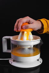 preparation of orange juice with squeezer on a black background, concept of healthy living