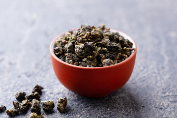 Green tea oolong in a clay tea cup bowl. Grey stone background. Close up. - obrazy, fototapety, plakaty