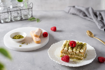 Vegan tiramisu with green matcha tea and raspberries on gray concrete background. Superfoods,...