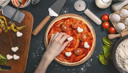 Classic pizza margherita with heart-shaped mazarella cheese. preparing a phased gala dinner for two...
