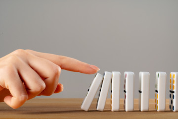 Woman hand toppling dominoes. Chain reaction business concept