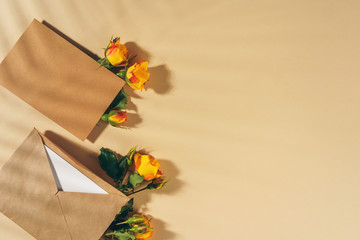 Craft paper envelope with yellow roses on beige background