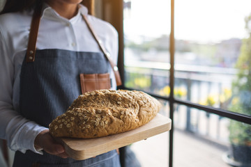 A waitress holding and serving a loaf of whole grain bread