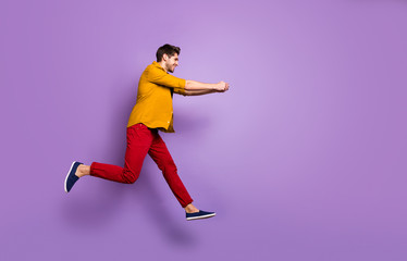 Fototapeta na wymiar Full length profile side photo of cheerful funky guy jump run hold hand copyspace try pull rope in game wear casual style clothing isolated over violet color background
