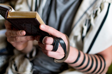 Reading Jewish prayer and a hand with tefillin and talit.