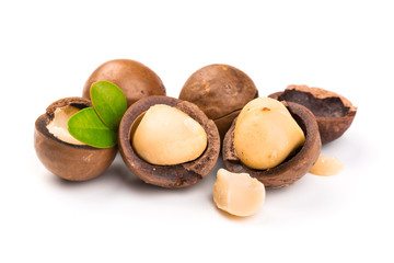 Macadamia nut with pieces and green leaves isolated on a white background