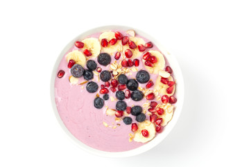 Berry smoothie bowl topped with blueberries, pomegranate seeds and bananas. Healthy breakfast smoothie bowl isolated on white background. Top view. 