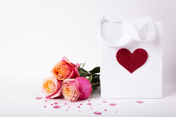 Roses and present gift in paper pack with red heart on white background/ Valentines day background