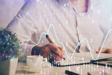 Double exposure of man's hands writing notes of stock market with forex chart.